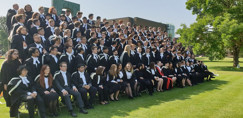 Students in graduation gowns sit in rows for a photo