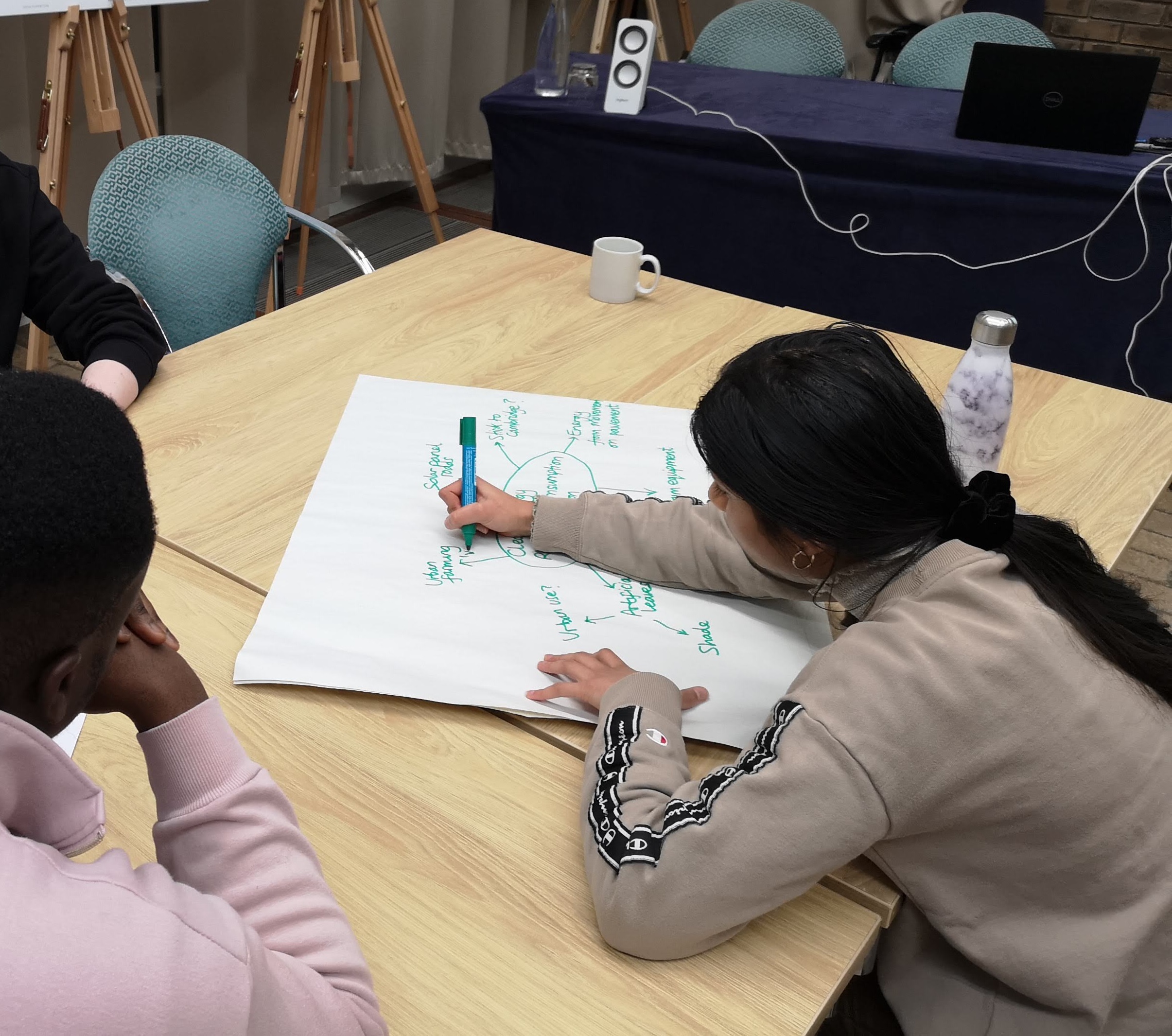 a student writing on a large piece of paper on a table