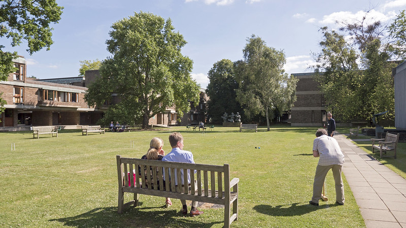 alumni on a bench watching croquet in Churchill College grounds