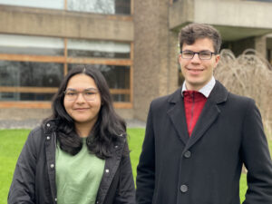 A pair of young people positioned in front of a contemporary structure